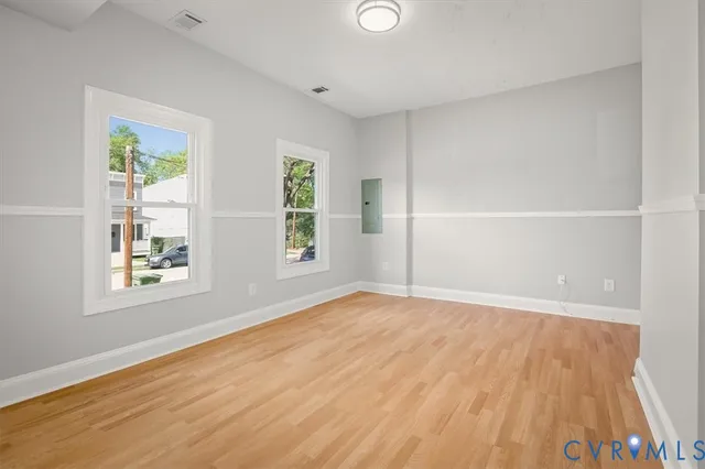 an empty room with wooden floor and windows
