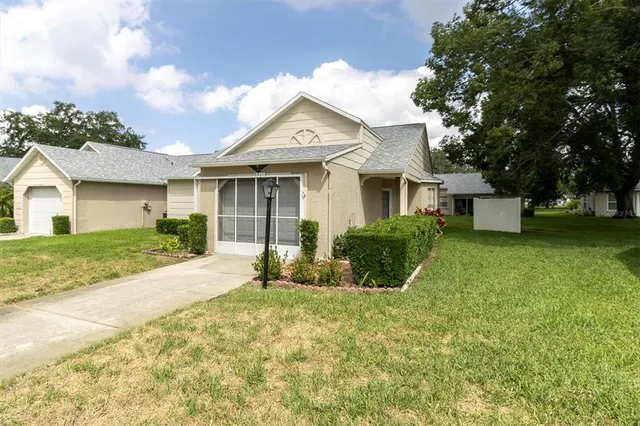 a view of a white house next to a yard with big trees