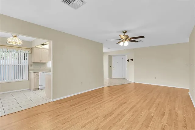 an empty room with wooden floor and ceiling fan