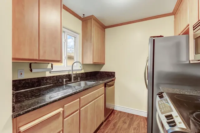 a kitchen with granite countertop a sink stove and refrigerator