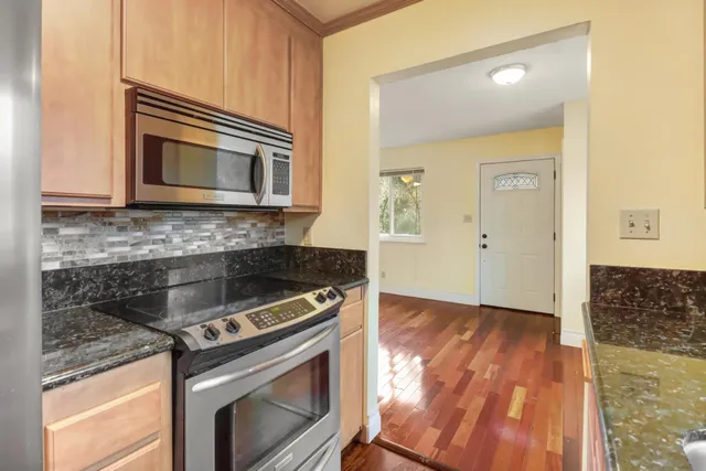 a view of a hallway with wooden floor and a bathroom