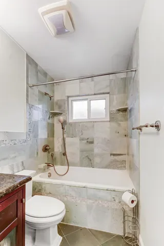 a bathroom with a granite countertop sink a toilet and shower