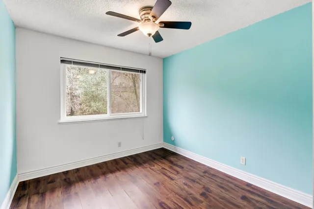 an empty room with wooden floor closet and ceiling fan