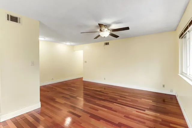 a view of empty room with wooden floor and fan