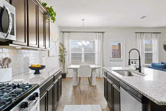 a kitchen with granite countertop a sink stove and cabinets