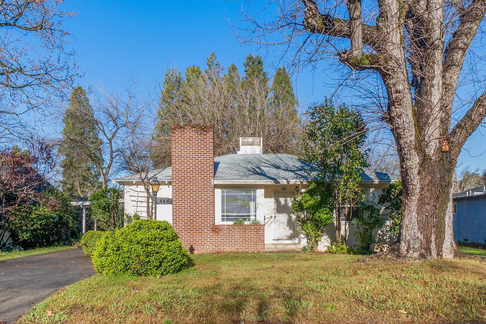 a view of a house with a large tree and a yard