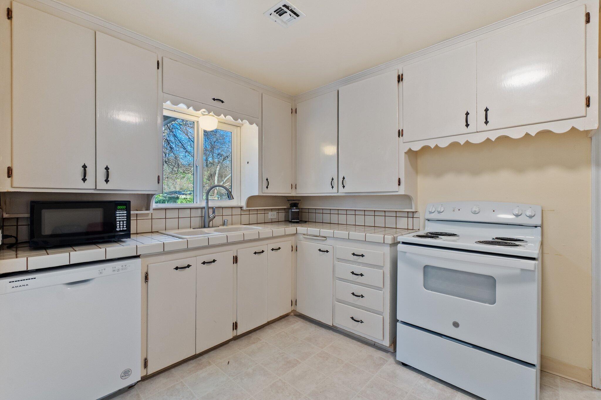 686 Coronado Street Redding, CA 96003 - Photo 14 of 39 a kitchen with granite countertop a stove sink and cabinets