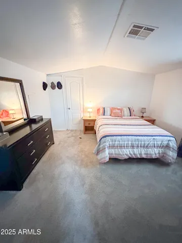 a bedroom with a bed and a flat tv screen on dresser