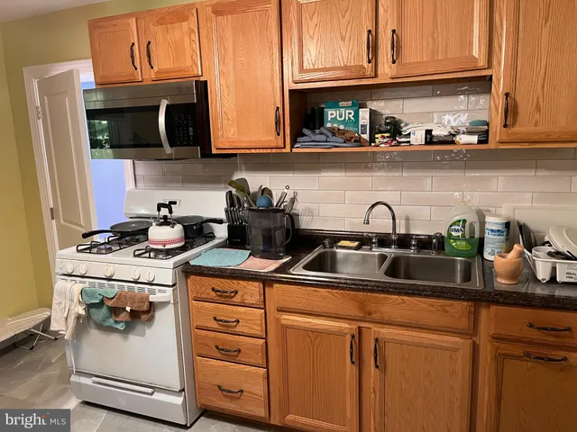 a kitchen with stainless steel appliances granite countertop a sink stove and microwave with cabinets