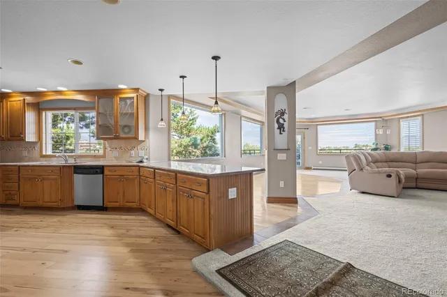 a large kitchen with stainless steel appliances kitchen island granite countertop a large counter top and a wooden floors