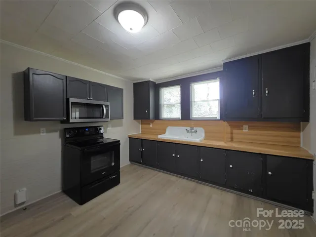 a large kitchen with stainless steel appliances granite countertop a large stove a sink dishwasher and a microwave oven with wooden floor