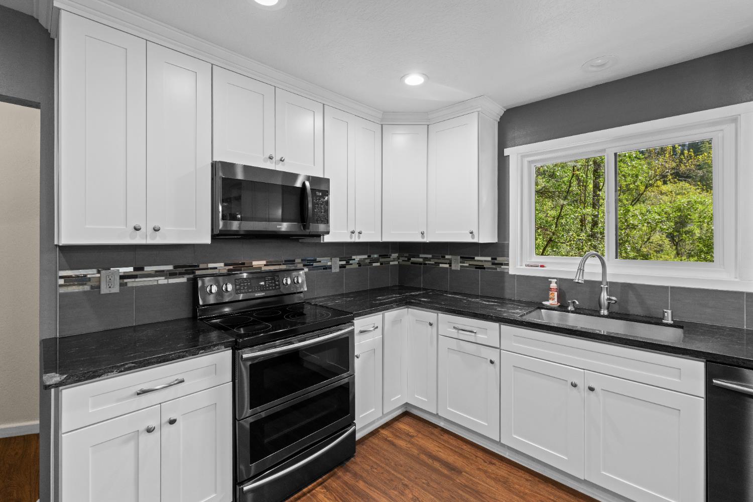 16173 Norlene Way Grass Valley, CA 95949 - Photo 6 of 25 a kitchen with white cabinets and a stove top oven