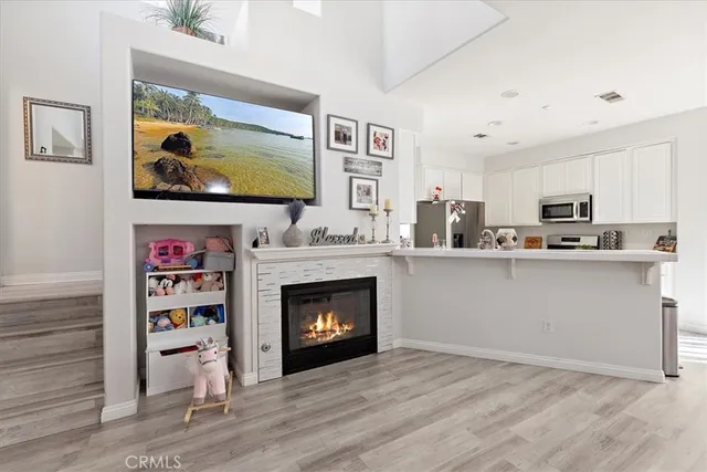 a living room with stainless steel appliances kitchen island furniture and a fireplace