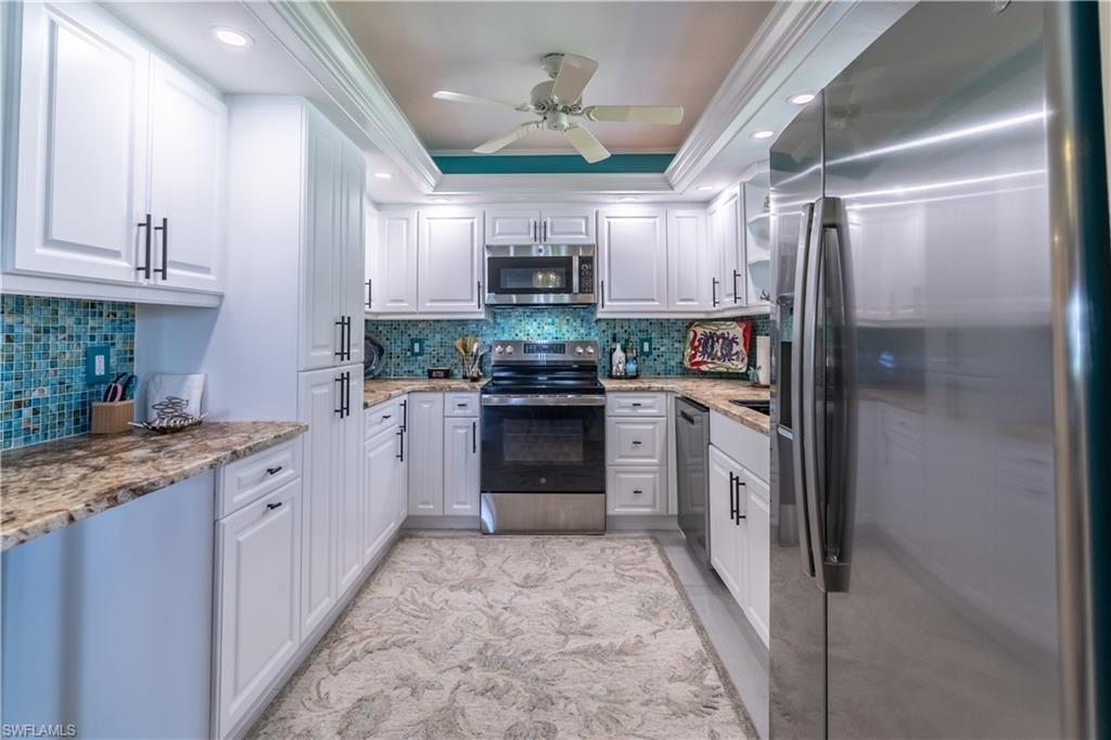 1071 8th Street South, Unit 103 Naples, FL 34102 - Photo 12 of 31 a kitchen with stainless steel appliances granite countertop a refrigerator a oven a sink with a stove and cabinets