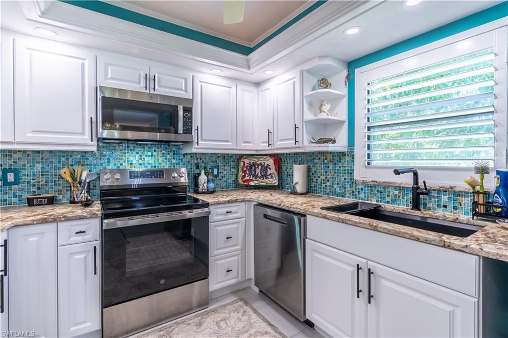 1071 8th Street South, Unit 103 Naples, FL 34102 - Photo 13 of 31 a kitchen with granite countertop a sink cabinets stainless steel appliances and a window