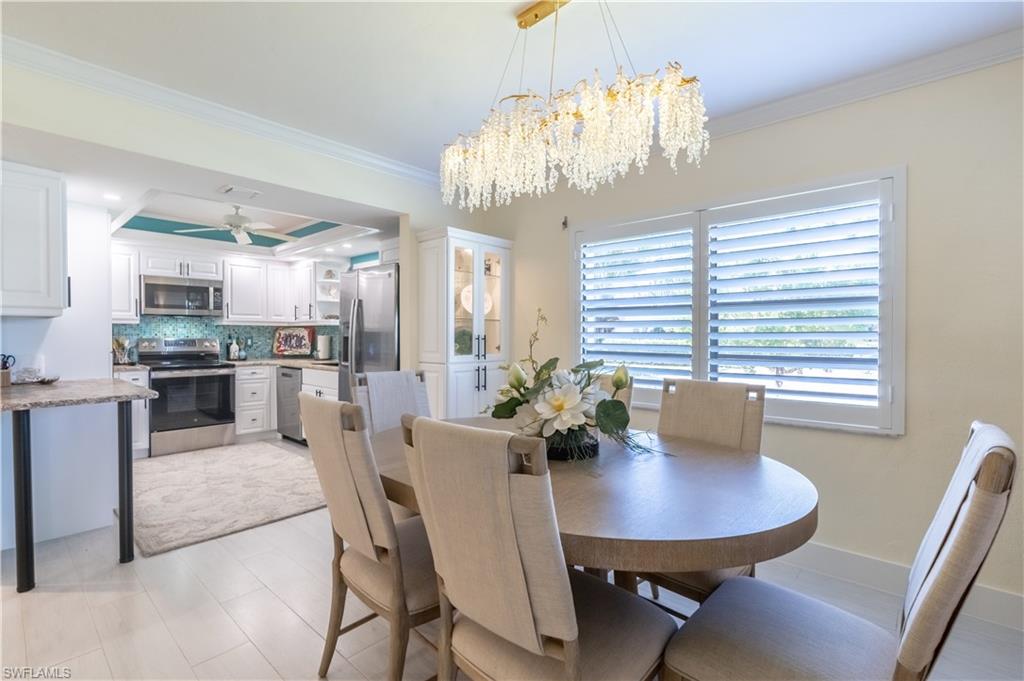 1071 8th Street South, Unit 103 Naples, FL 34102 - Photo 10 of 31 a view of a dining room with furniture a chandelier and wooden floor