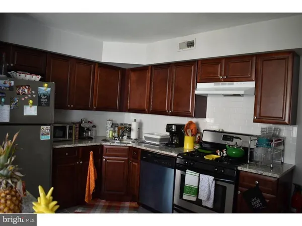 a kitchen with granite countertop a sink dishwasher stove and cabinets