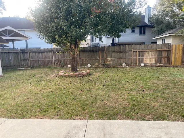 a backyard of a house with large trees and brick wall
