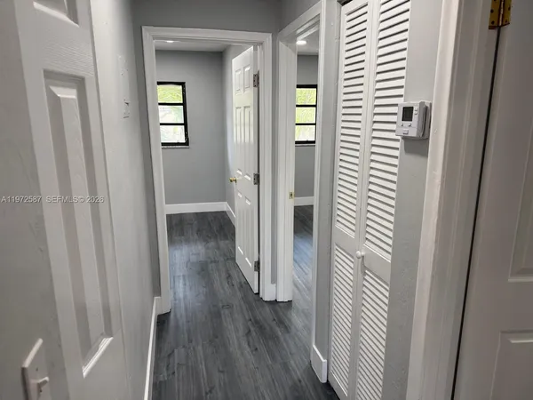 a view of a hallway with wooden floor and closet area