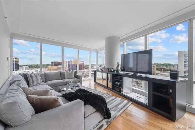 a living room with furniture large windows and wooden floor