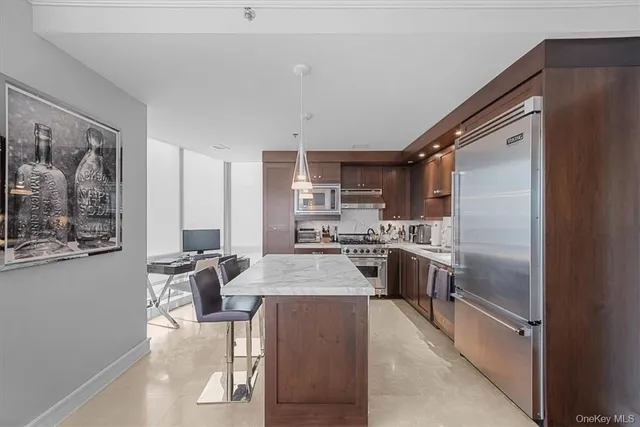 a large kitchen with kitchen island a large counter space a sink stainless steel appliances and cabinets