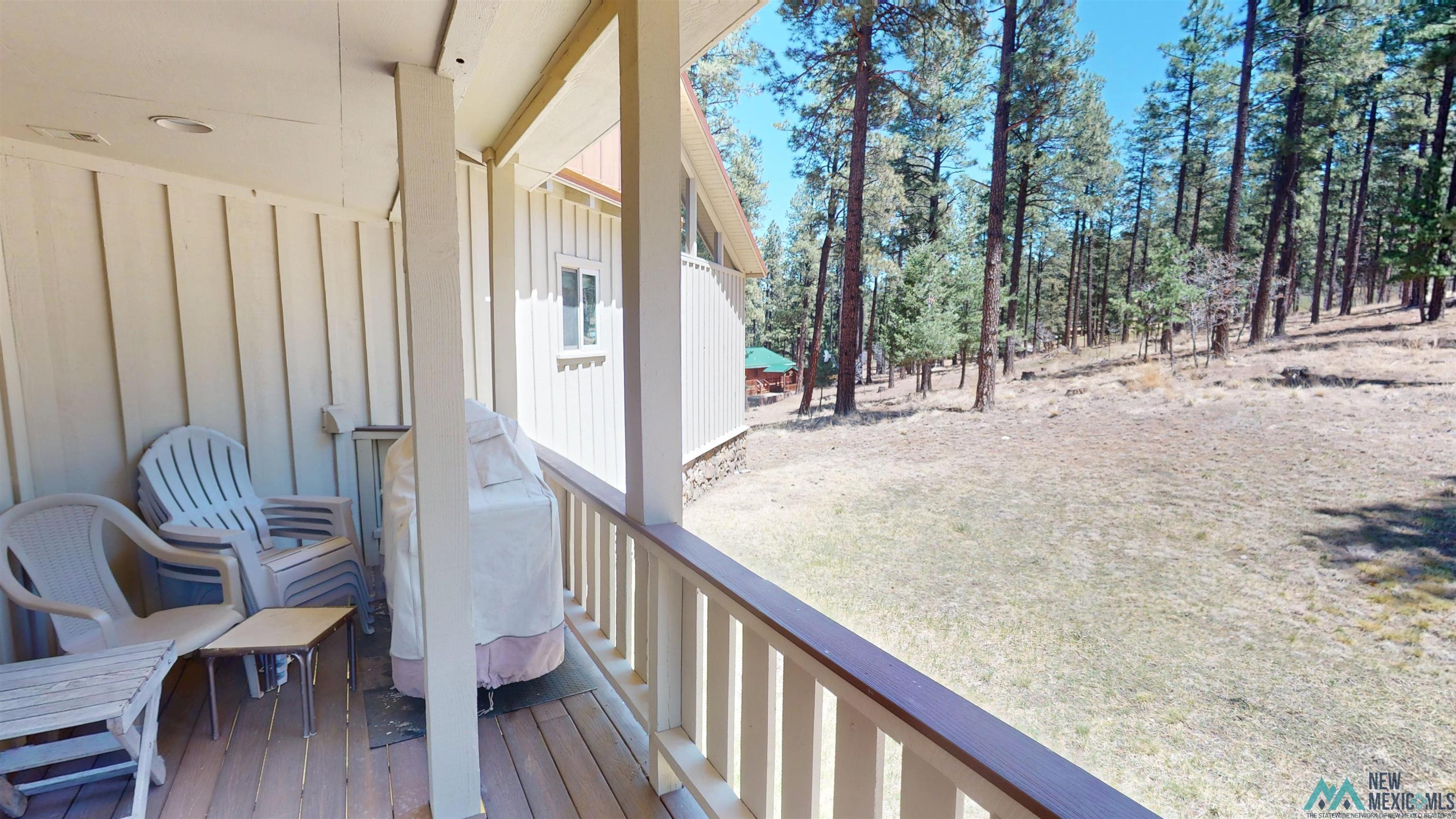 39 Alta Vista Rociada, NM 87742 - Photo 50 of 54 Wood-plank outdoor deck with a natural wood railing and vertical panel siding