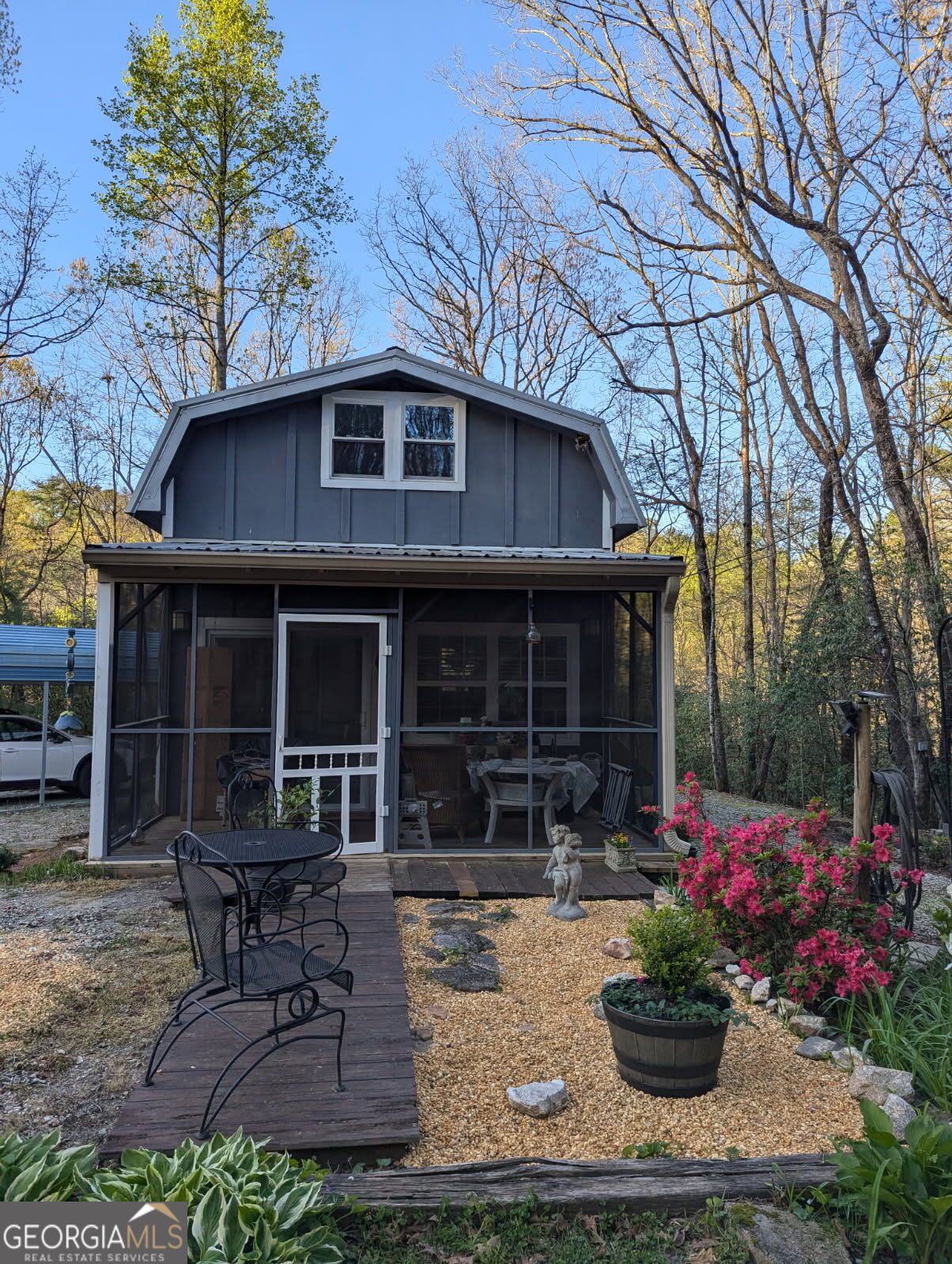 a view of house with yard outdoor seating and covered with trees