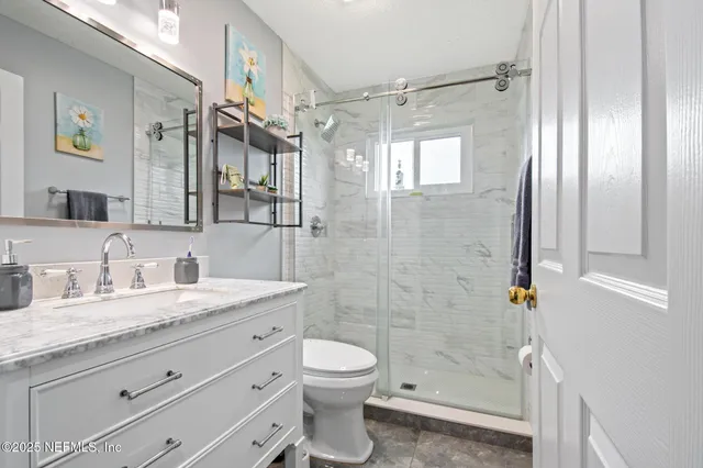a bathroom with a granite countertop shower sink vanity mirror and toilet