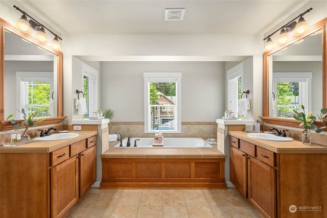 a spacious bathroom with a double vanity sink bathtub and next to a window