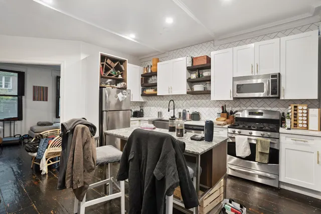 a kitchen with stainless steel appliances granite countertop a stove top oven a sink a dining table and chairs with wooden floor