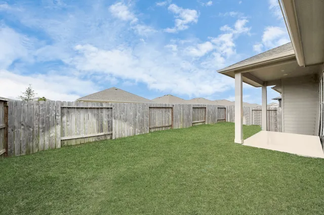 a view of a house with a yard and wooden fence