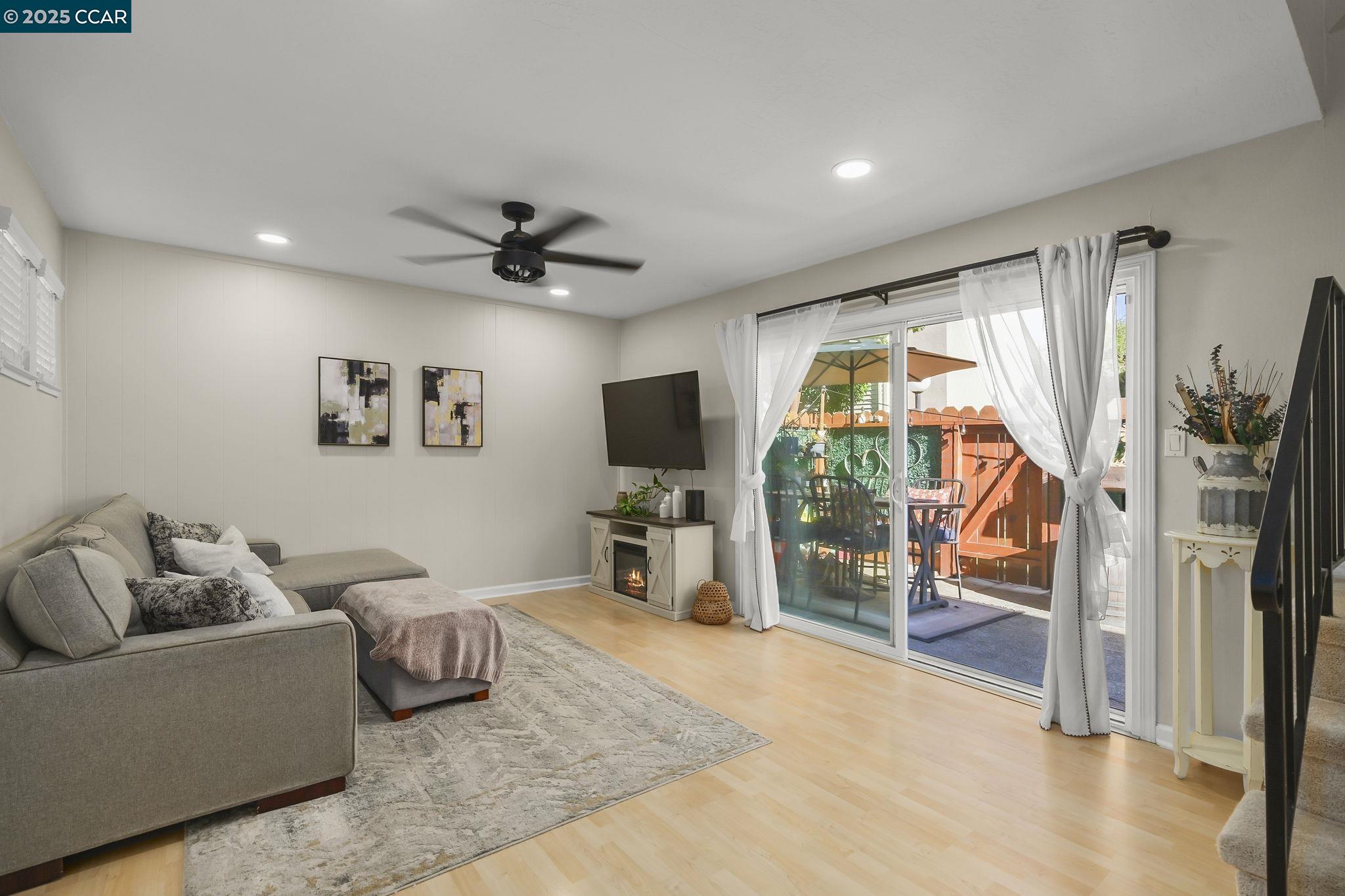 1435 Bel Air Drive, Unit C Concord, CA 94521 - Photo 6 of 25 a living room with furniture a flat screen tv and a floor to ceiling window