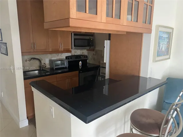 a kitchen with stainless steel appliances granite countertop a sink a stove and a microwave with wooden floor