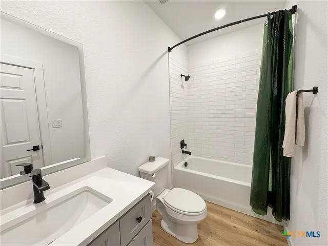 a bathroom with a sink a toilet a mirror and shower