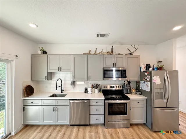 a kitchen with kitchen island white cabinets and stainless steel appliances