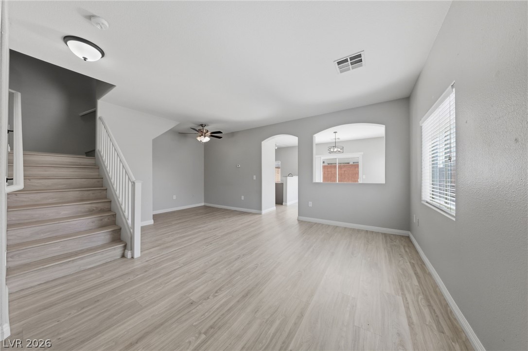 6312 Sandy Ridge Street, Unit 3102 North Las Vegas, NV 89081 - Photo 4 of 31 A well-proportioned living area features light wood flooring, a staircase with white railings, and a subtle archway leading to another room.
