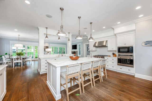 a kitchen with stainless steel appliances kitchen island granite countertop a table chairs and a wooden floor