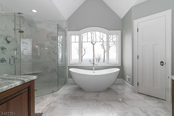a bathroom with a granite countertop double vanity sink and mirror with window