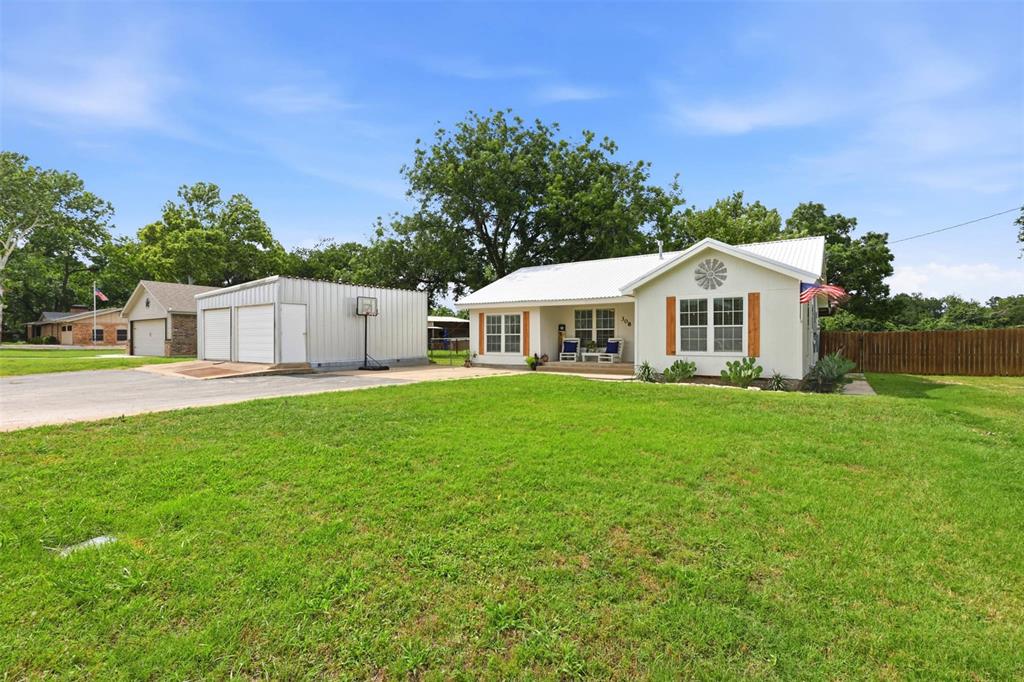 308 West 1st Street Springtown, TX 76082 - Photo 2 of 39 White exterior residence with a metal roof and decorative wooden shutters