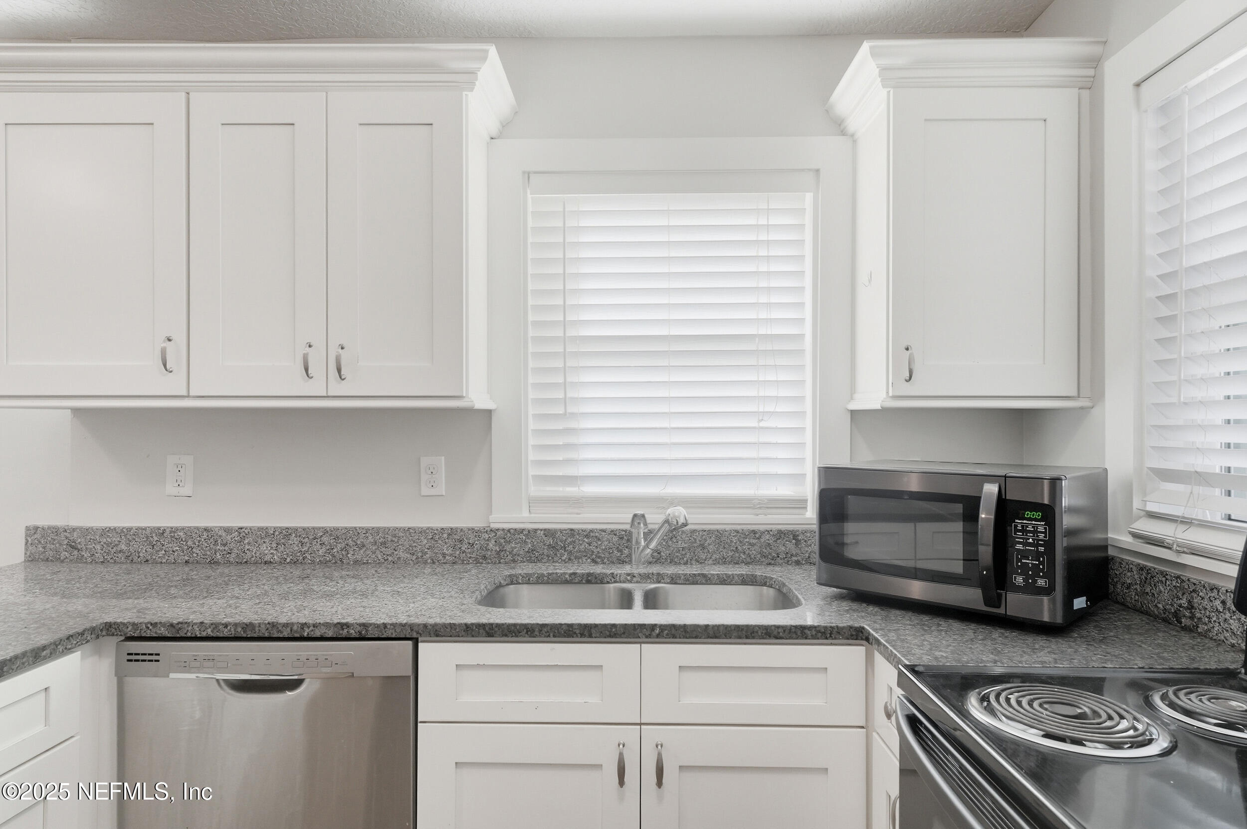 1211 Penman Road Jacksonville Beach, FL 32250 - Photo 12 of 44 a kitchen with granite countertop stainless steel appliances white cabinets granite counter tops and a wooden floor