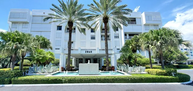 a front view of multi story residential apartment building with yard and green space