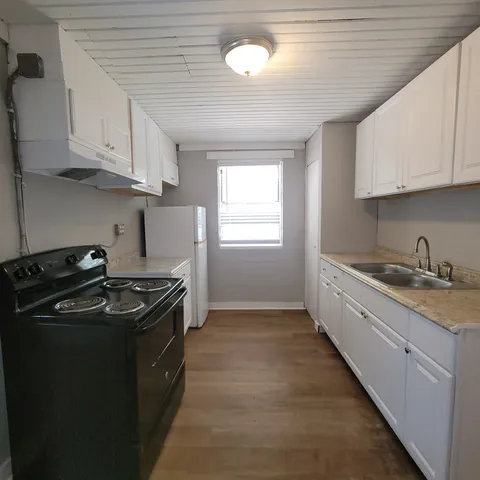 a kitchen with granite countertop a sink stove and cabinets