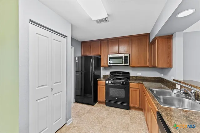 a kitchen with stainless steel appliances granite countertop a stove a sink and a microwave