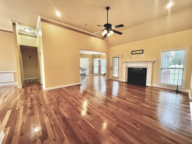 a view of an empty room with wooden floor fireplace and a window