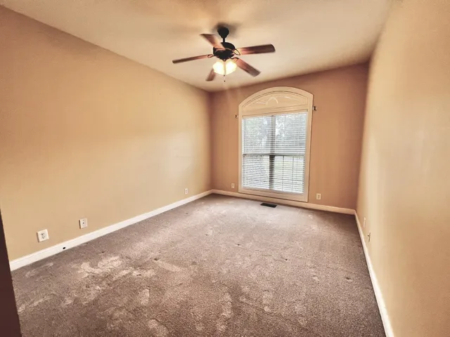 an empty room with windows and fan