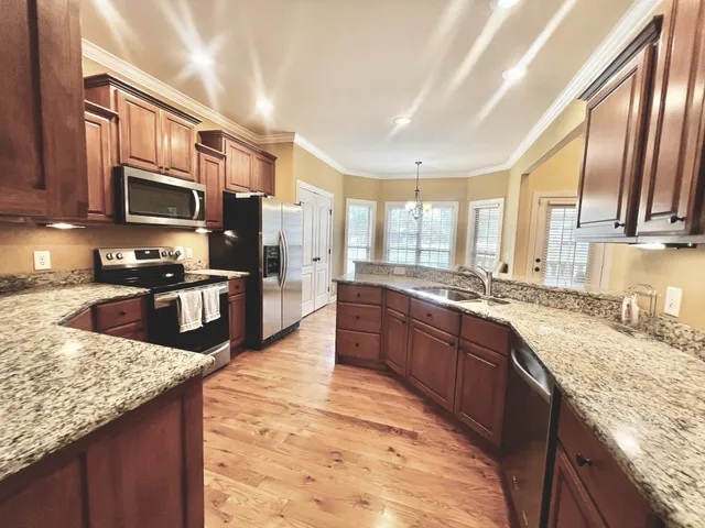 a large kitchen with granite countertop lots of counter top space and stainless steel appliances