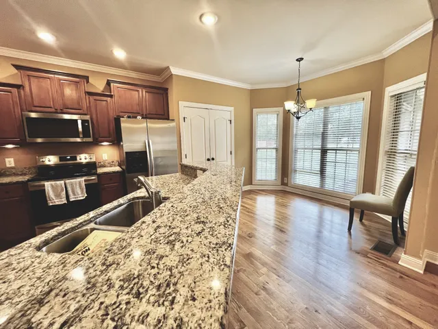 a living room with stainless steel appliances kitchen island granite countertop furniture and a wooden floor