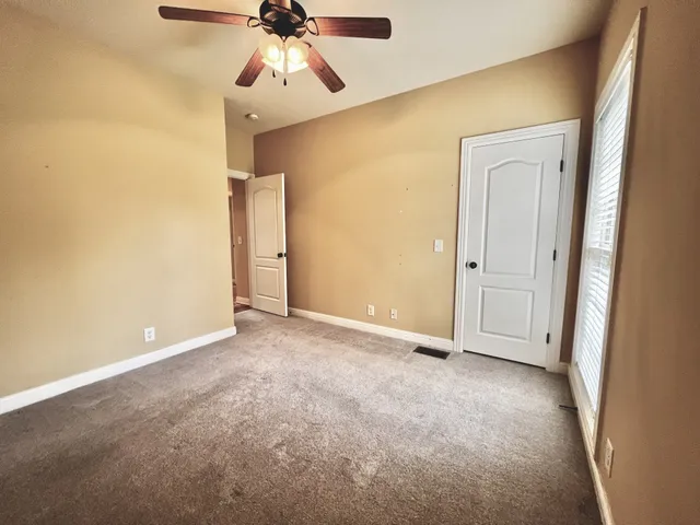 an empty room with closet and a chandelier fan