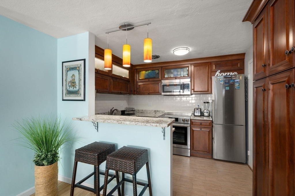 31 Warren Street, Unit B1 Waltham, MA 02453 - Photo 2 of 22 a kitchen with stainless steel appliances granite countertop a refrigerator a stove a sink dishwasher and a refrigerator with wooden floor