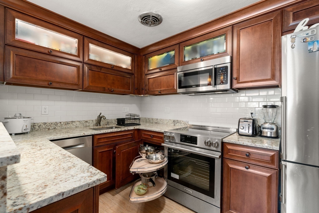 31 Warren Street, Unit B1 Waltham, MA 02453 - Photo 5 of 22 a kitchen with stainless steel appliances granite countertop a stove and a microwave